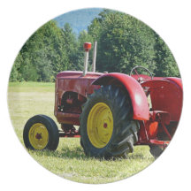 Antiker roter und gelber Traktor auf dem Gebiet Teller