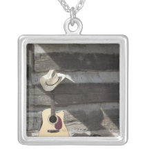 Cowboyhut auf der Gitarre, die auf Blockhaus sich  Personalisierte Halskette