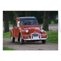 Ein altes rotes Auto Citroen 2CV mit einer lächeln Grußkarte