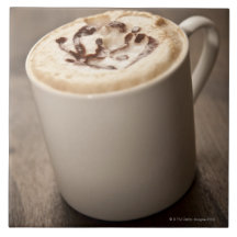 Ein Becher Cappuccinokaffee überstieg mit geschmol Fliesen