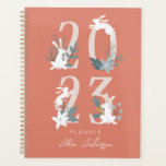 2023 Red Winter Floral & Foliage Bunny Planner Planer<br><div class="desc">Dieser niedliche 2023-Planer besticht durch eine weiße Holzhütte mit Winterblumen und Blattwerk auf rotem Hintergrund. Auf der Rückseite befindet sich ein bordeauxroter Hintergrund mit botanischen Mustern. Personalisieren Sie es für Ihre Bedürfnisse.</div>