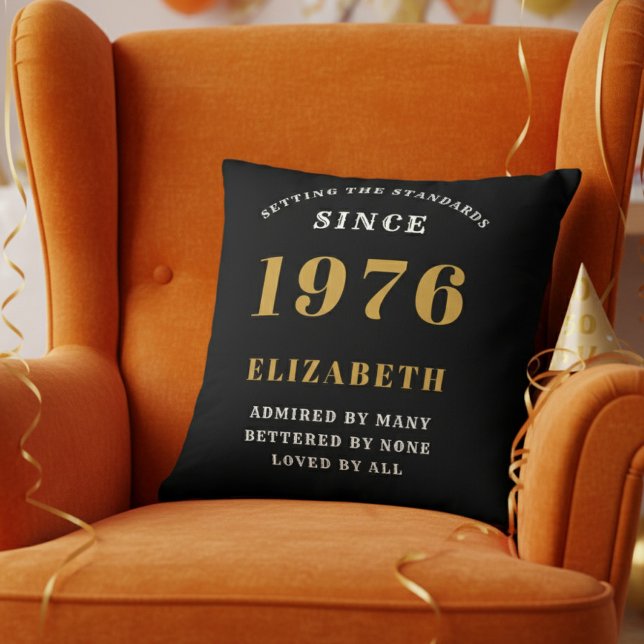 50th Birthday Gift Personalized 1976 Black Gold Kissen (Personalized 50th birthday pillow on a vibrant orange velvet wingback chair)