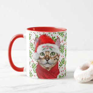 Abessinienkatze in einer Weihnachtsmannmütze mit H Tasse