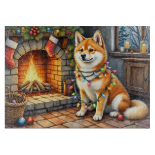 Akita sitzt neben dem Kamin mit Weihnachtslichtern Schneidebrett