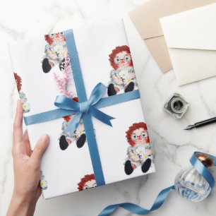 alte Flickenpuppe mit Gänseblümchenstrauß Geschenkpapier