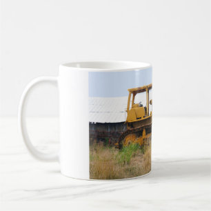 Alter gelber Bulldozer, der auf einer Weide gepark Tasse