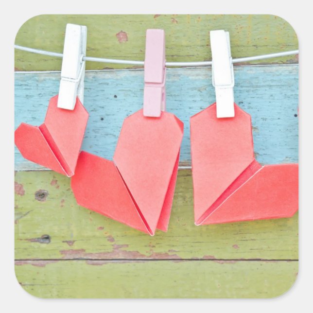 An der Wäscheleine hängende Papierherz Quadratischer Aufkleber (Vorderseite)