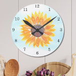 Aquarellblume Runde Wanduhr<br><div class="desc">Diese Uhr ist mit einer gelben, wasserfarbenen Sonnenblume und blauem Himmelshintergrund geschmückt. Das ist ein Erwärmung-Geschenk. Original Wasserfarbe © Michele Davies.</div>