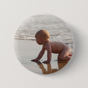 Baby, das im Sand auf dem Strand spielt Button