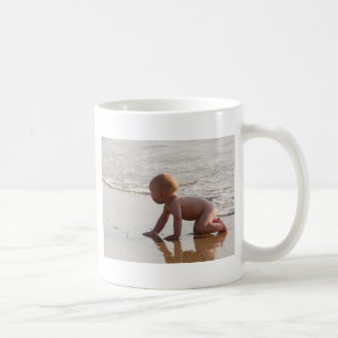 Baby, das im Sand auf dem Strand spielt Tasse
