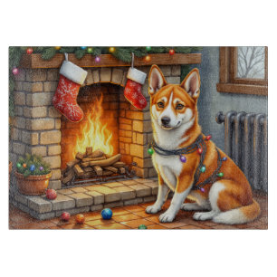 Basenji sitzt neben dem Kamin mit Weihnachtsbeleuc Schneidebrett