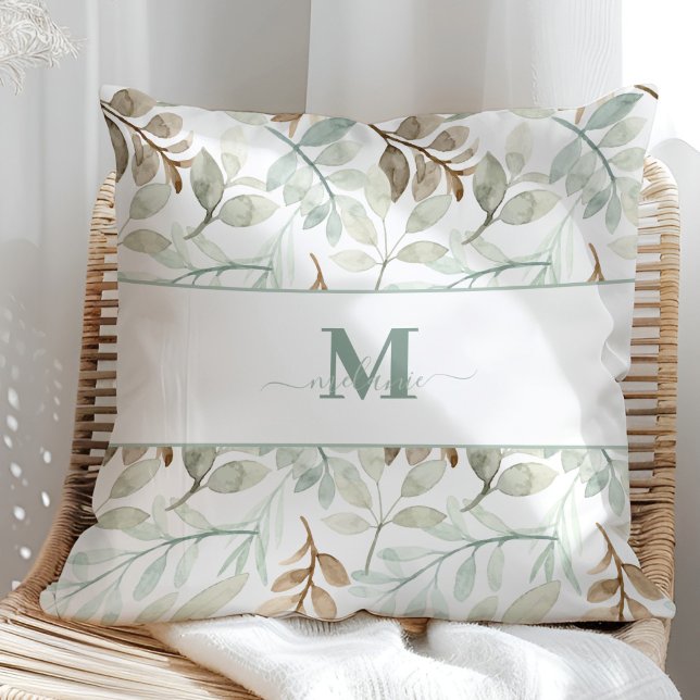 Blätter mit Individuelle Name und Anfangsfarben Kissen (Watercolor leaves with Custom Name and Initial Throw Pillow in a sunny rattan armchair.)