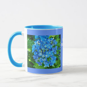 blaue Hortensienblüten und ihre grünen Blätter Tasse
