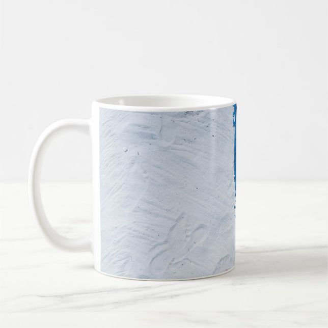 Blauer und schwarzer Blumenschal auf weißem Sand Kaffeetasse (Links)