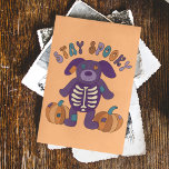 Bleibe Spooky Niedlich Skeleton Hund Halloween Postkarte<br><div class="desc">Die Nachricht auf der Vorderseite dieser Postkarte liest BLEIBE SPOOKY über einer niedlichen Abbildung eines gestopften Hundes im Patchwork-Stil mit einem Skelett auf seinem Bauch und ein paar Kürbisse aus Patchwork. Die Rückseite dieser Karte ist leer,  damit Sie Ihre eigene Nachricht schreiben können.</div>
