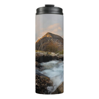 BRAUNER BERG IN DER NÄHE EINES GEWÄSSERS UNTER BED THERMOSBECHER