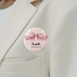 Bridesmaid bow rosa Namensmarke Button<br><div class="desc">Ein weich rosa,  rosa Hintergrund. Mit einem großen Bogen dekoriert. Personalisieren Sie den Namen Ihrer Brautjungfrau und fügen Sie ihn hinzu. Schwarzes handgeschriebenes Stilskript.</div>