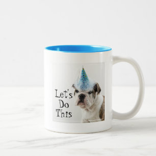 Britischer Bulldoggen-Welpe, der einen Party-Hut Zweifarbige Tasse