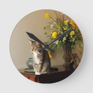 Brown schwarze Tabbykatze, die auf Klavier-Blumen Runde Wanduhr