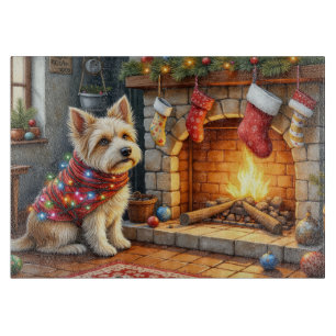 Cairn Terrier sitzt vor dem Kamin mit Weihnachtsbe Schneidebrett