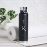 Chic Monogram auf schwarz Trinkflasche<br><div class="desc">Das elegante,  weiße,  vertikale Monogramm auf schwarz zeichnet sich durch eine größere dekorative Initiale in der Mitte aus. Ersetzen Sie die 3 Initialen durch Ihre eigene in der Sidebar. Weitere Farben und Stile der Wasserflasche sind in der Sidebar erhältlich. Copyright © Claire E. Skinner. Alle Rechte vorbehalten.</div>