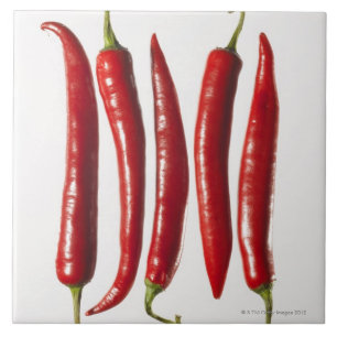 Chili-Paprikaschoten in einer Reihe Fliese