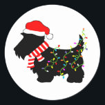 Christmas Scottie Dog mit Licht Runder Aufkleber<br><div class="desc">Schottische Hundeliebhaber von Terrier werden diesen festlichen,  schwarzen Scottie Dog mit einer Weihnachtsmannmütze,  rot-weiß gestreiften Schal und bunten Saitenleuchten genießen! Erleben Sie den Weihnachtsgeist mit diesem lustigen Design auf anpassbaren Geschenken!</div>