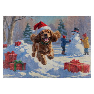 Cocker Spaniel läuft im Schnee mit Weihnachtsmütze Schneidebrett