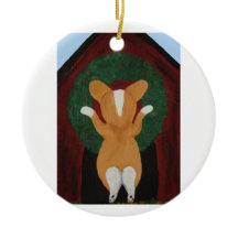 Corgi hängt Weihnachtskranz an das Hundehaus