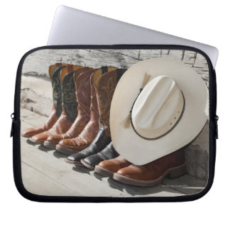 Cowboy-Hut in Reihe von Cowboy-Stiefeln außerhalb  Laptopschutzhülle