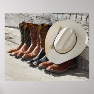 Cowboy-Hut in Reihe von Cowboy-Stiefeln außerhalb Poster