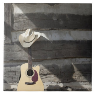 Cowboyhut auf der Gitarre, die auf Blockhaus sich Fliese