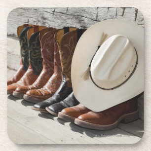 Cowboyhut auf Reihe der Cowboystiefel außerhalb Untersetzer