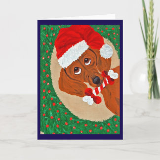 Dachshund Weihnachtsmann, der durch einen Kranz sc Karte