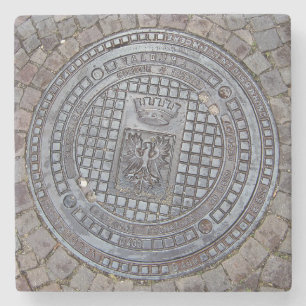 Deckel eines Kanalschachts und Kopfsteinpflaster-S Steinuntersetzer