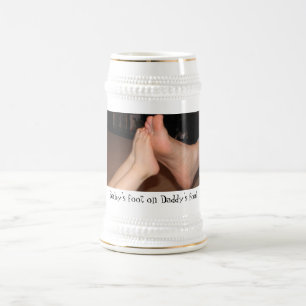 Der Fuß des Babys auf dem Fuß des Vatis Bierglas