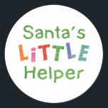 Der kleine Helfer des Weihnachtsmanns Runder Aufkleber<br><div class="desc">Ein festliches,  farbenfrohes Weihnachtsdesign für Kinder. Liest "Der kleine Helfer des Weihnachtsmanns" in Regenbogenfarben.</div>