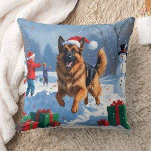 Deutscher Schäferhund läuft im Schnee mit Weihnach Kissen