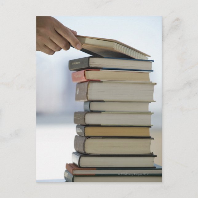 Die Hand des Mannes, die ein Buch von einem Stapel Postkarte (Vorderseite)