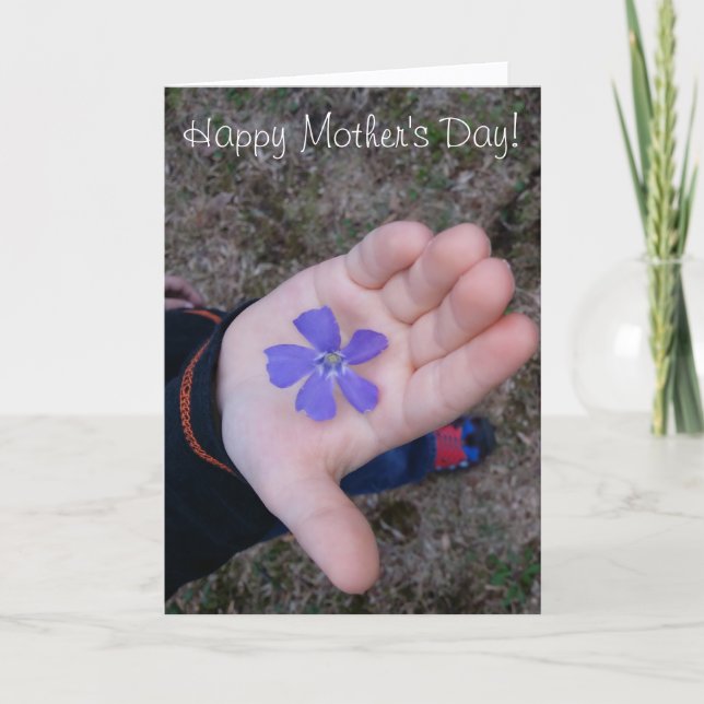 Die Hand des Muttertagkindes, das Lila Blume gibt Karte (Vorderseite)