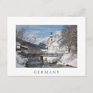 Die Kirche im Schnee mit den Alpen im Winter Postkarte