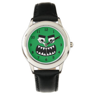Die lustige Kinderuhr mit grünem Monster gegenüber Armbanduhr
