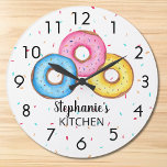 Donut Kitchen Personalisiert<br><div class="desc">Diese lustige Uhr ist mit drei Donuts in blau, rosa und gelb auf einem Sprinkle-Hintergrund dekoriert. Einfach mit Ihrem Namen anpassbar. Verwenden Sie die Option Weitere anpassen, um die Textgröße, den Stil oder die Farbe zu ändern, wenn Sie möchten. Weil wir unsere eigenen Kunstwerke erstellen, werden Sie dieses exakte Bild...</div>
