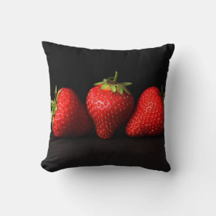 Drei Erdbeeren auf schwarzer Ebene Kissen
