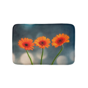 Drei Orange Gerberas in einer Row-Badematte Badematte