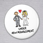 Ehepaar - unter neuer Leitung Magnet<br><div class="desc">Ein niedlicher Cartoon eines frisch verheirateten Paares mit dem Titel "unter neuer Leitung". Ist es die Braut oder der Bräutigam,  die die Hose in der Ehe trägt? Ideal für ein Hochzeitsgeschenk,  oder um Flitterwochen zu tragen.</div>