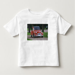 Ein altes, rotes Citroen 2CV Auto mit einer lächel Kleinkind T-shirt