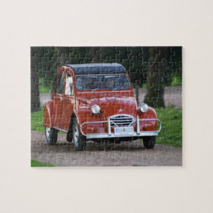 Ein altes, rotes Citroen 2CV Auto mit einer lächel Puzzle
