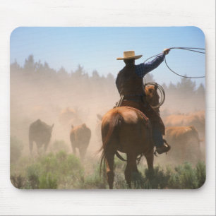 Ein Cowboy, der bei der Herde auf einer Rinder Mousepad