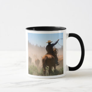 Ein Cowboy, der bei der Herde auf einer Rinder Tasse